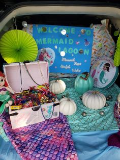 the trunk of a car is filled with mermaid themed items and decorations, including an umbrella