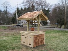 a small wooden structure with a potted plant on top in the middle of a field