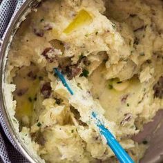 mashed potatoes in a metal bowl with a blue spoon next to it on a towel