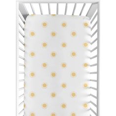 a white crib bed with yellow and white sun print on the sheets, in front of a white background