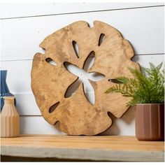 a wooden object sitting on top of a shelf next to a potted plant