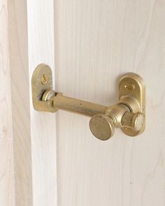 a door handle on a wooden door that is painted white and has gold knobs