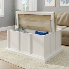 a white storage box sitting on top of a rug in front of a couch and window