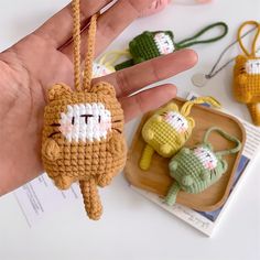 a hand holding a small crocheted cat ornament next to other items