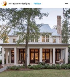 a white house with columns on the front and side porchs, surrounded by trees