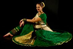 a woman sitting on the ground in a green and gold dress