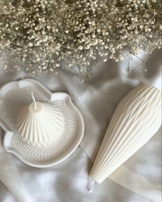 a vase filled with baby's breath flowers next to a candle holder on a white sheet