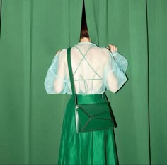 a woman in a green dress is standing with her back to the camera