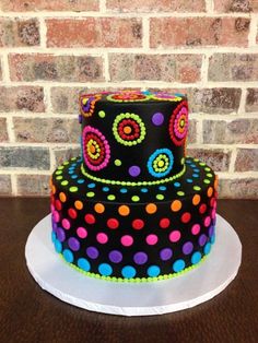 a three tiered cake decorated with multi colored polka dots