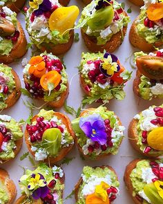 many small sandwiches are decorated with flowers and garnishes on top of them