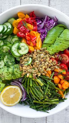 a white bowl filled with lots of different types of veggies and sliced oranges