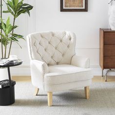 a white chair sitting next to a plant in a living room