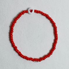 "At Marche Des Perles we make all our seed bead bracelets to order. The \"red heart bracelet\", inspired by our love of the breton stripe. A red heart, surrounded by red coloured beads on an elastic chain, tied neatly together at the end. We recommend not to pull too hard on the elastic or this could permanently stretch the bracelet, or worse, break it. we'd also suggest taking it off before showering to avoid discolouration or damage." Red Heart Bracelet, Parts Of The Heart, Red Beaded Bracelet, Bracelet Inspired, Bead Bracelets, Seed Bead Bracelets, Red Bead, Heart Beads, Heart Bracelet