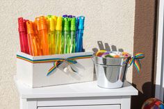 there are many colorful pens in the box on the table next to the bucket and ball