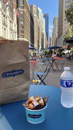 a blue table topped with a bowl of food next to a bag of chips and a bottle of water