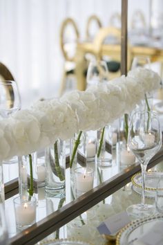 the table is set with candles and flowers in glass vases, along with wine glasses