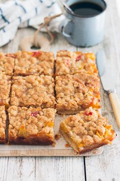 several squares of food sitting on top of a cutting board next to a cup of coffee