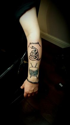 a person with a tattoo on their arm holding a coffee cup and spoon in front of them