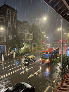 a city street at night in the rain with cars and buses driving down the road