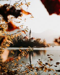 an image of a lake that is surrounded by trees and buildings in the distance with mountains in the background