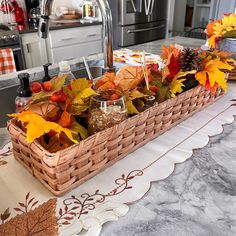 a basket filled with autumn leaves on top of a kitchen counter