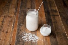 a glass jar filled with white powder next to a spoon on top of a wooden table