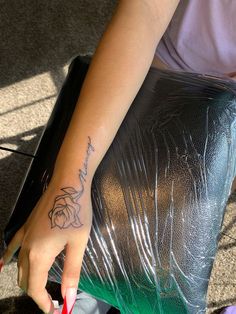 a woman's hand with a tattoo on her left arm holding a piece of luggage