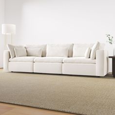 a white couch sitting on top of a carpeted floor next to a wooden table