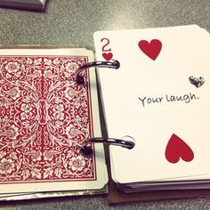 an open notebook with playing cards on it and the words your laugh written in red