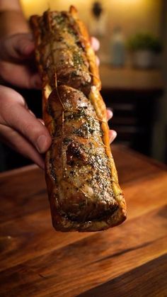 a person holding a piece of meat on a wooden table