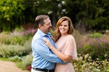 a man and woman standing next to each other in front of some flowers on the ground