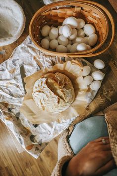 bread and eggs are sitting on the table next to each other, with a basket full of them