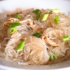 a white bowl filled with noodles and green onions