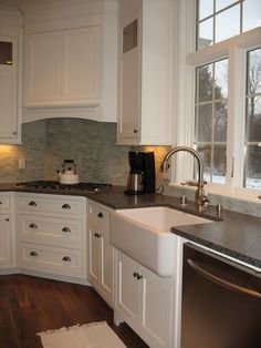 a kitchen with white cabinets and black counter tops, along with a dishwasher