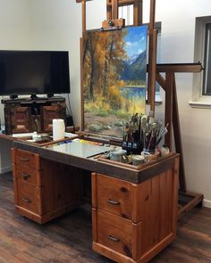 an easel with paint, pencils and other art supplies on it in front of a painting