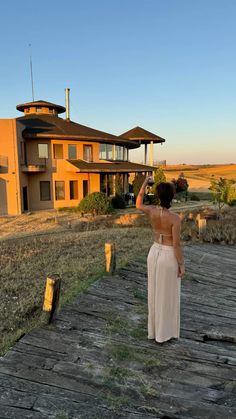 a woman standing on a wooden walkway in front of a house