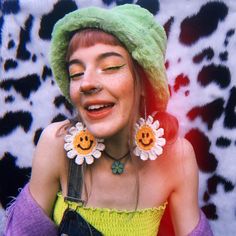 a woman in a green hat and yellow dress with flowers on her ear is smiling