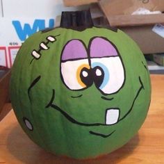 a green pumpkin with an angry face painted on it