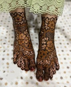 the legs and feet of a woman with henna tattoos on their hands, both decorated with flowers