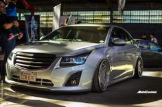 a silver car is parked in front of some people