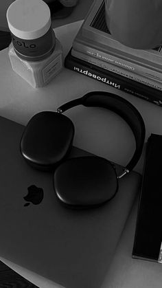 an apple laptop computer sitting on top of a desk next to headphones and books