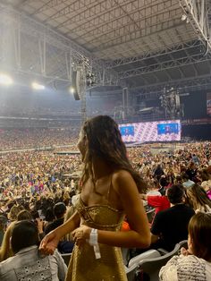 a woman standing in front of a crowd at a sporting event wearing a gold dress