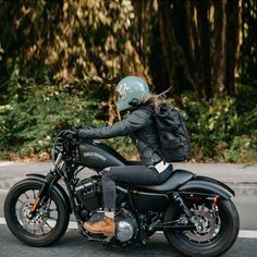 a person riding on the back of a motorcycle down a street with trees in the background