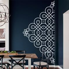 a dining room with a table and chairs in front of a blue wall that has an intricate design on it