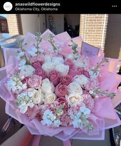 pink and white flowers in a bouquet on top of a table with greeting cards attached to it