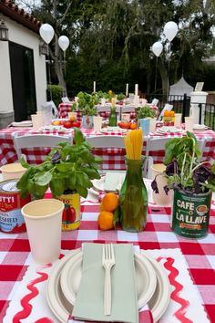 a table set with plates, cups and utensils for an outdoor dinner party