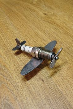 a small metal airplane sitting on top of a wooden table next to a corkscrew