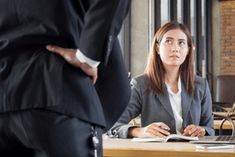 a woman sitting at a desk in front of a man