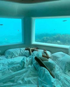 a woman is laying in bed under the water and looking out from an underwater bedroom