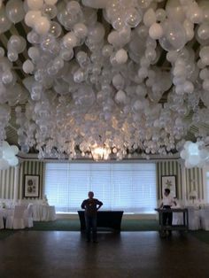 a man sitting in front of a window surrounded by balloons